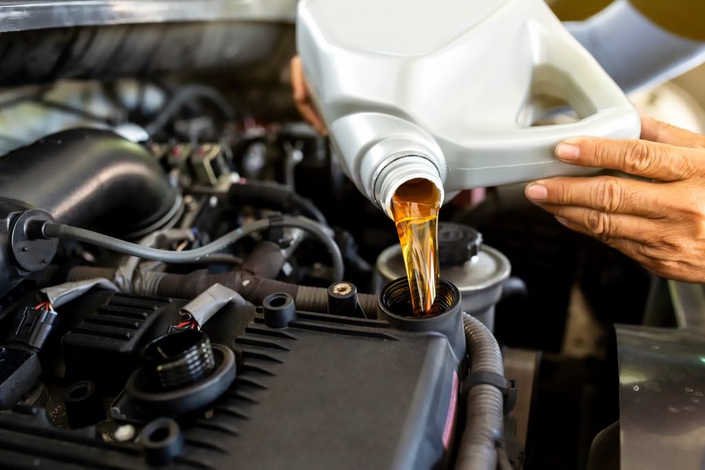 Automechanik lejúci nový olej do motora auta. 